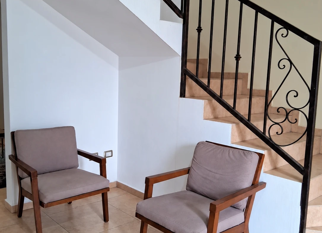 Escaleras con barandal de herrería y área de descanso en la casa amueblada en Saltillo