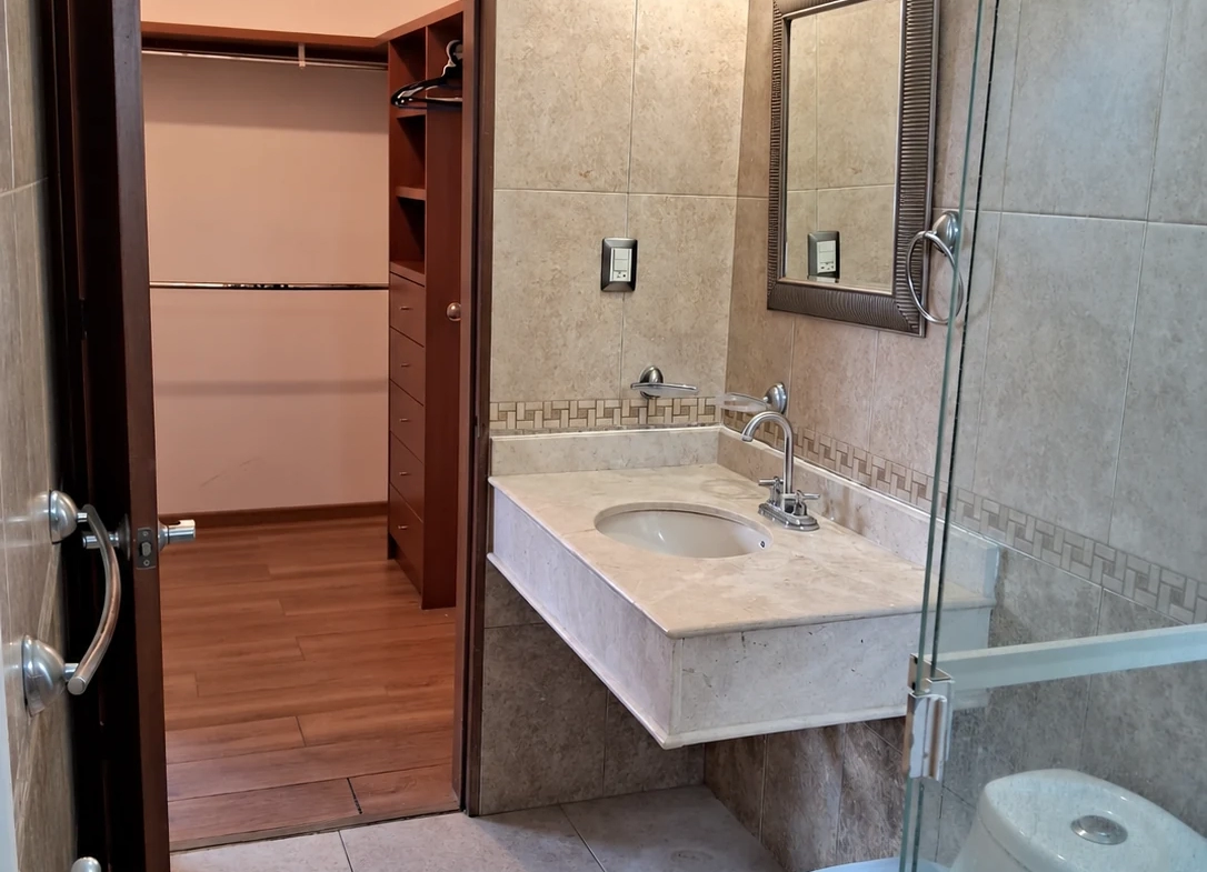 Baño con cancel de cristal, lavabo y acceso al vestidor de la casa en Saltillo